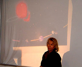 Janet Luhmann talking against a projected background with Earth's orbit